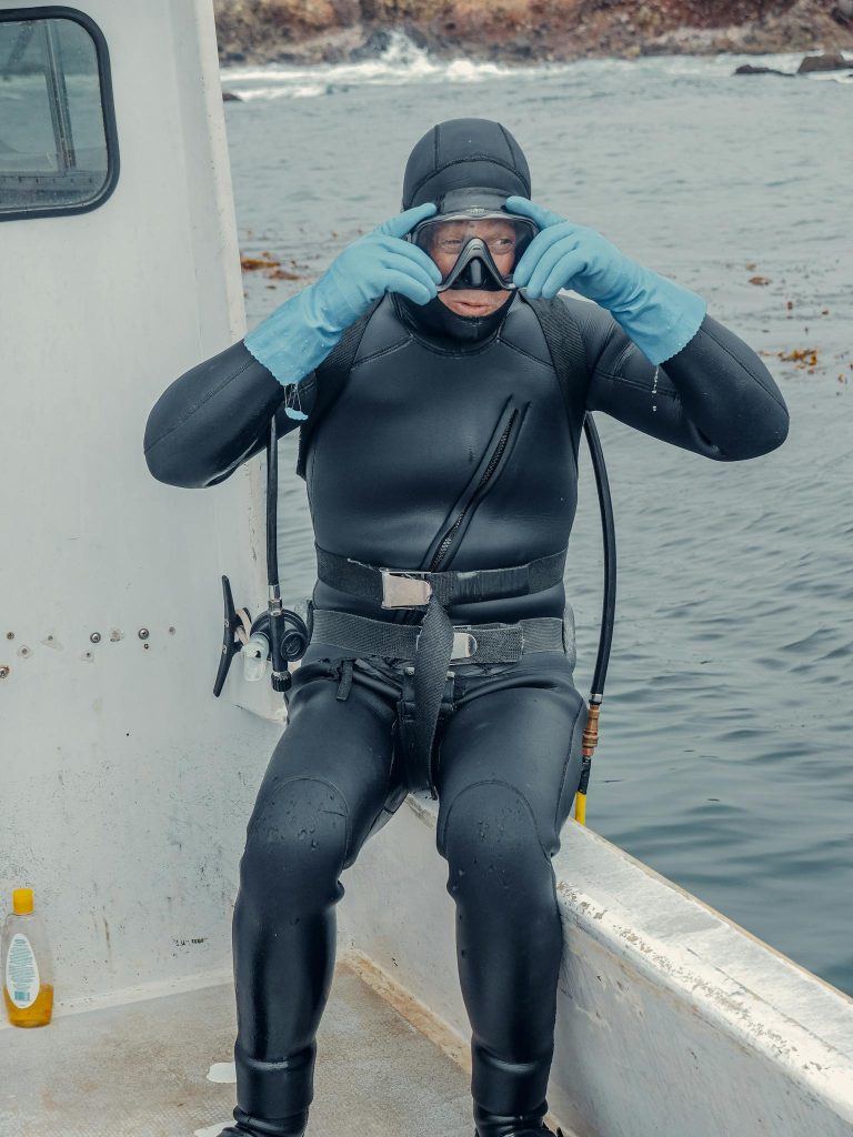 A scuba diver in full gear sits on a boat, ready for an underwater adventure.